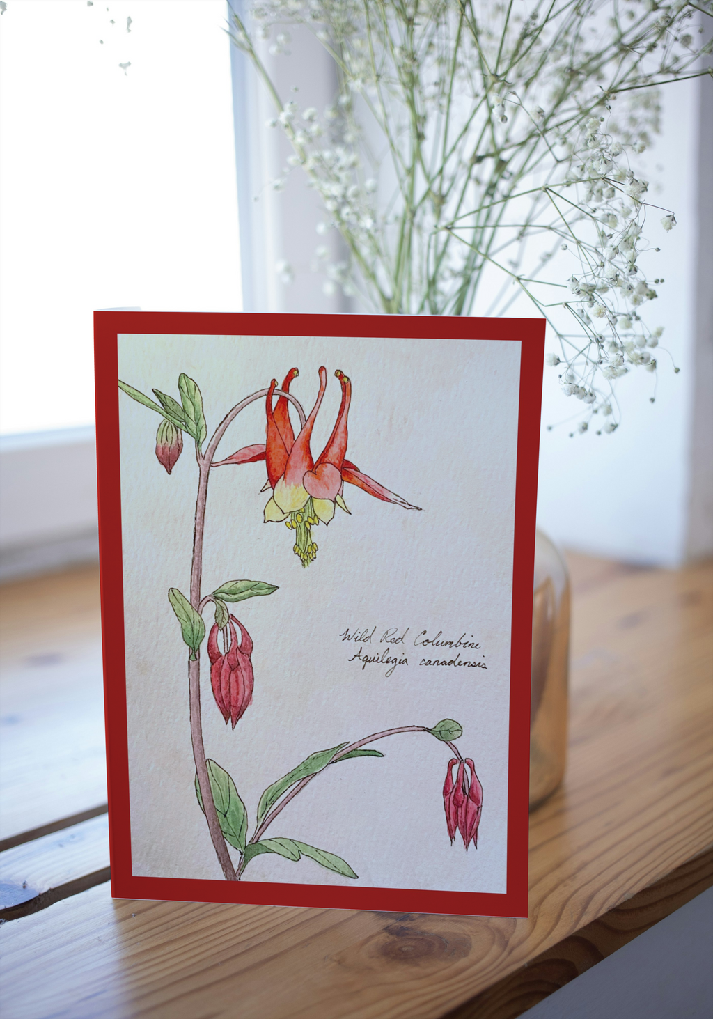 Card with red border featuring a botanical illustration of red flowers on a wooden surface.