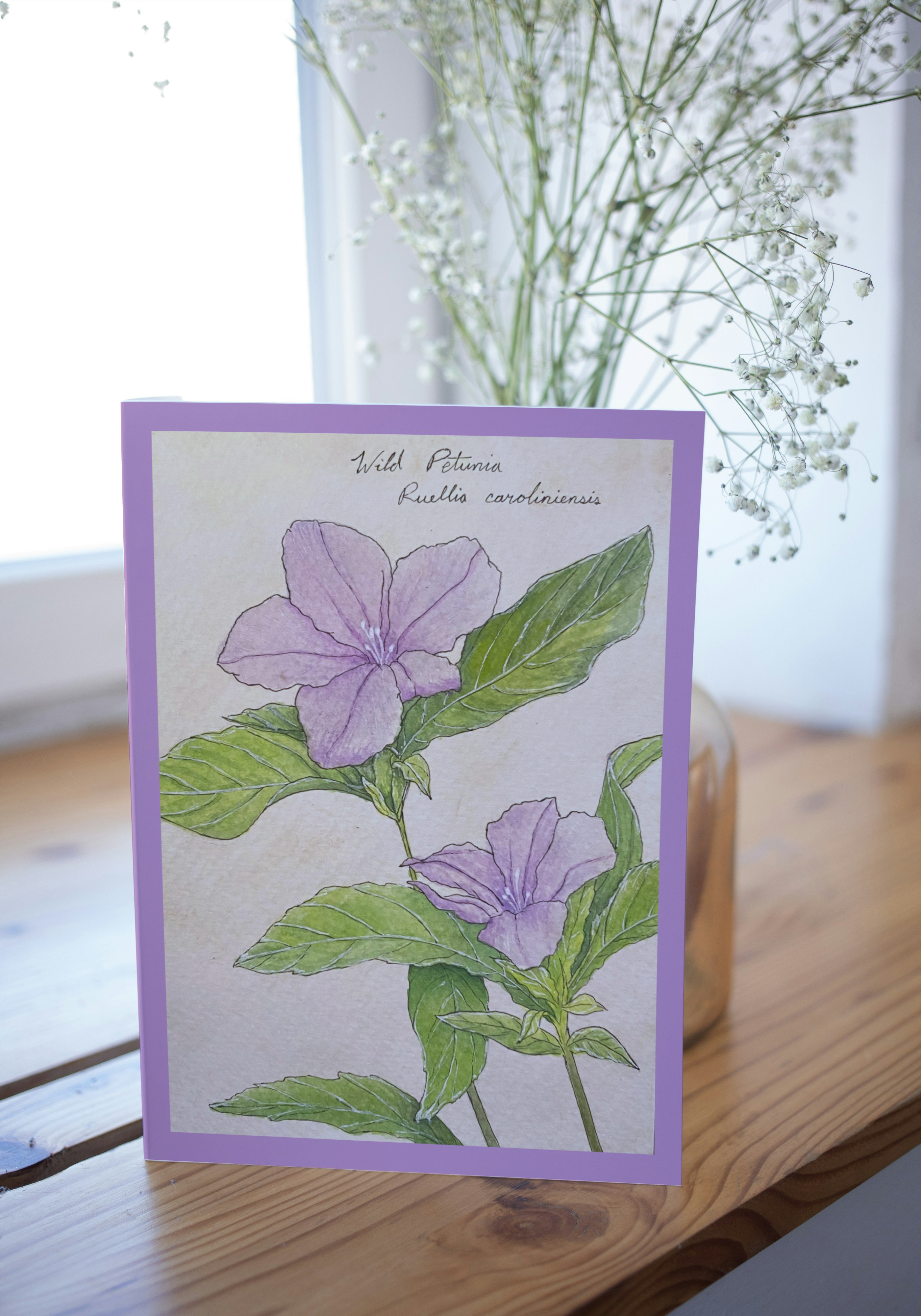 Card with purple flowers and green leaves on a wooden surface with a blurred background