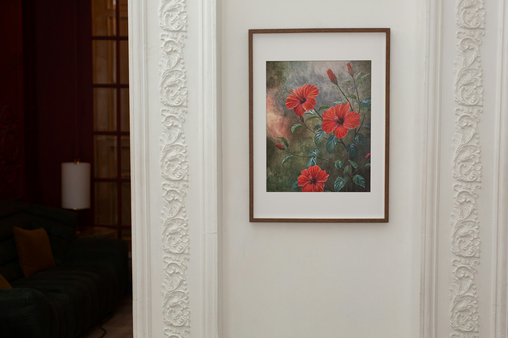 Framed painting print of red hibiscus flowers on a white wall