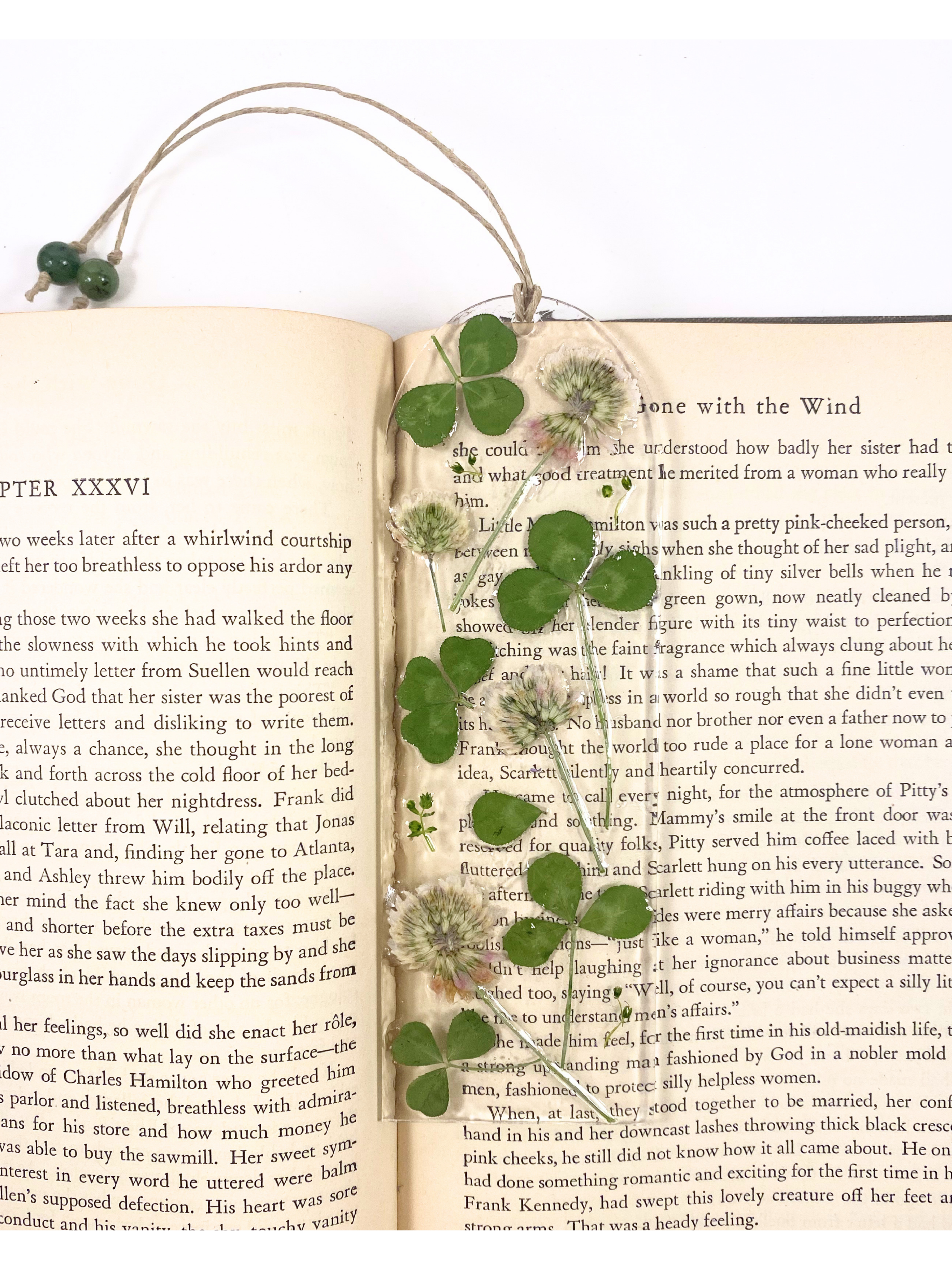 A bookmark featuring clover flowers and leaves, displayed on an open book.