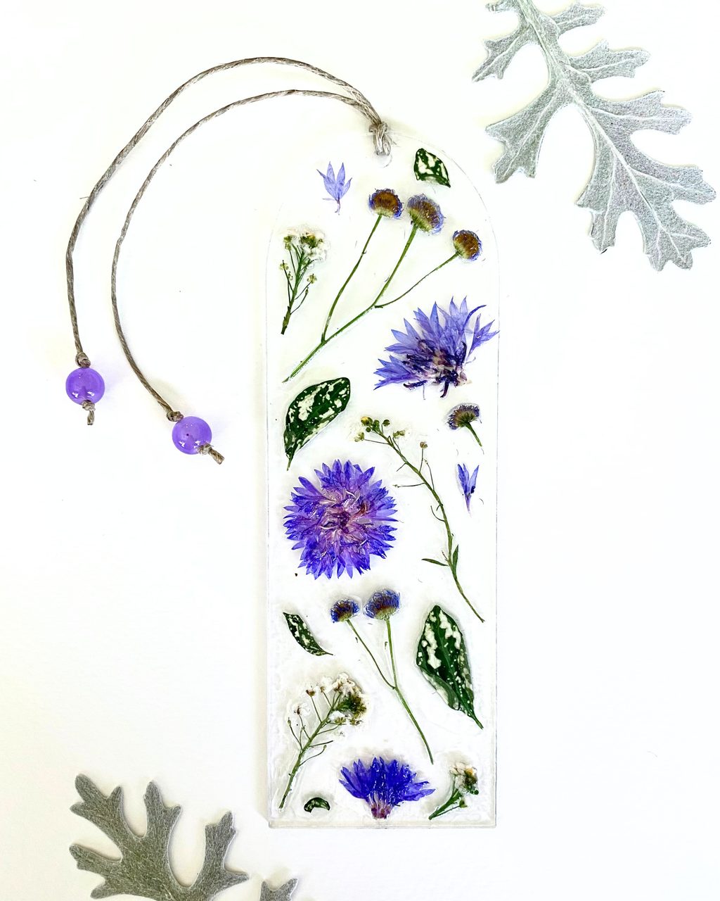 A bookmark with purple flowers and green leaves on a white background