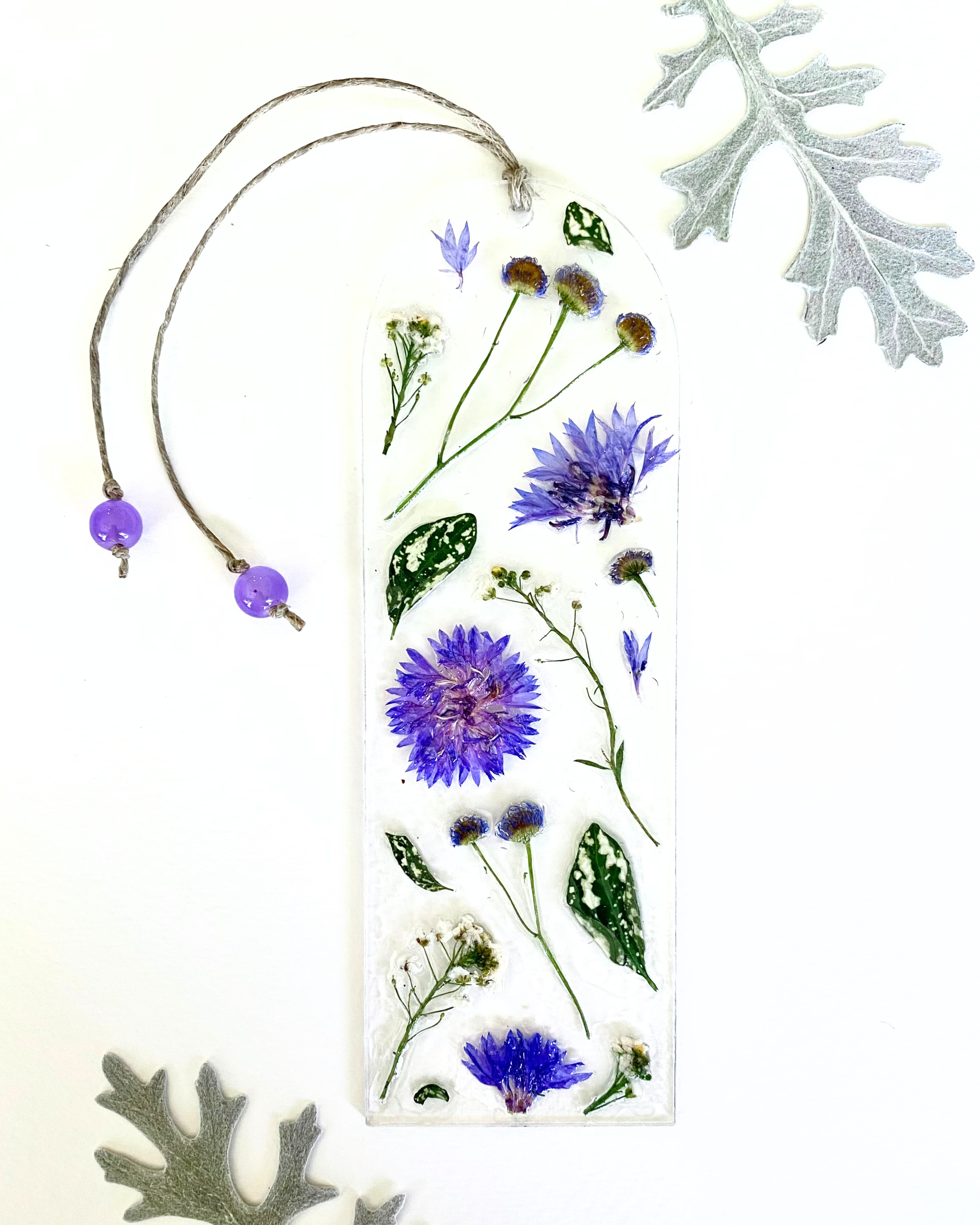A bookmark with purple flowers and green leaves on a white background