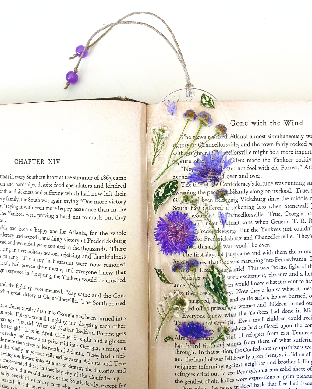A bookmark with purple flowers and green leaves in a book