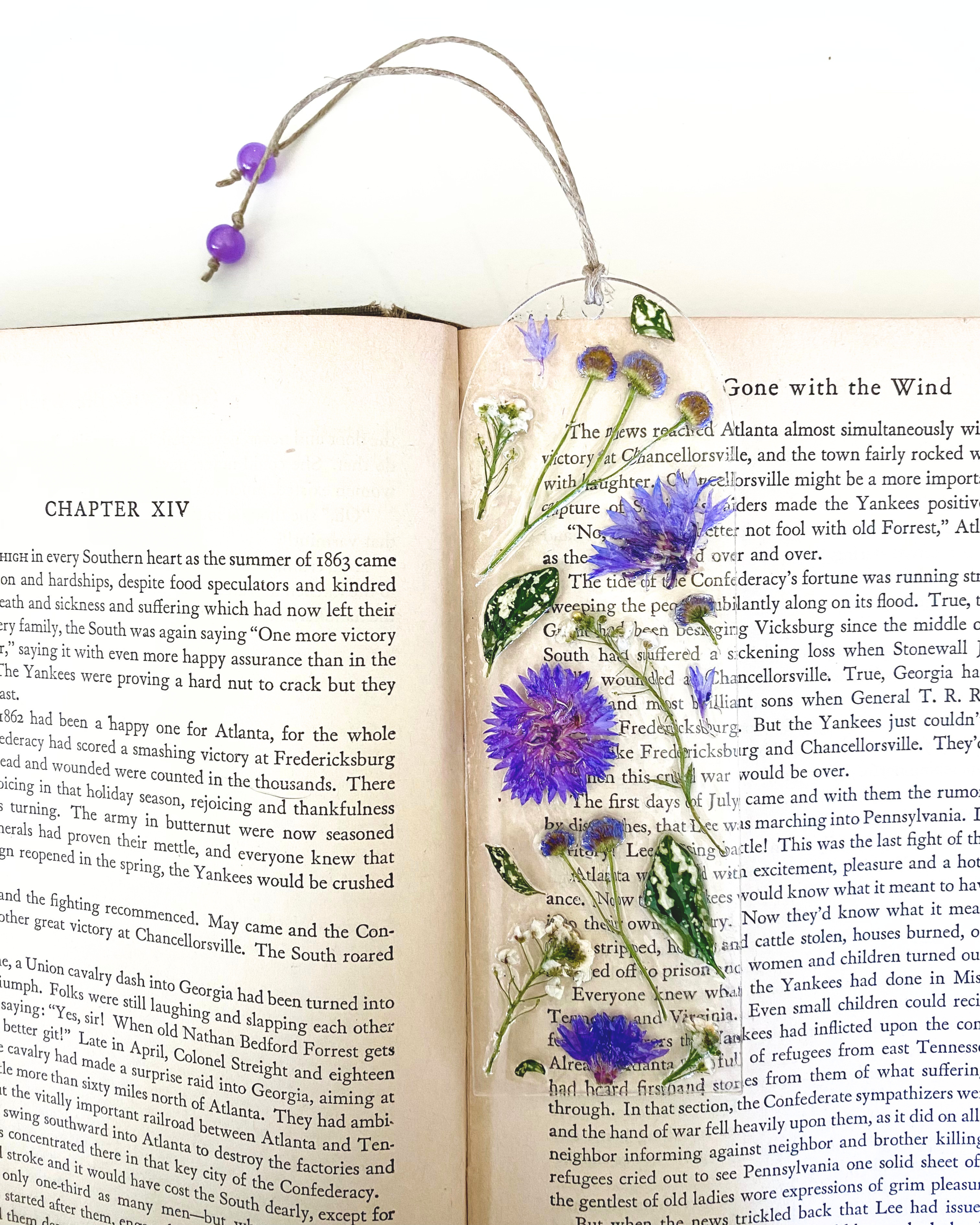 A bookmark with purple flowers and green leaves in a book